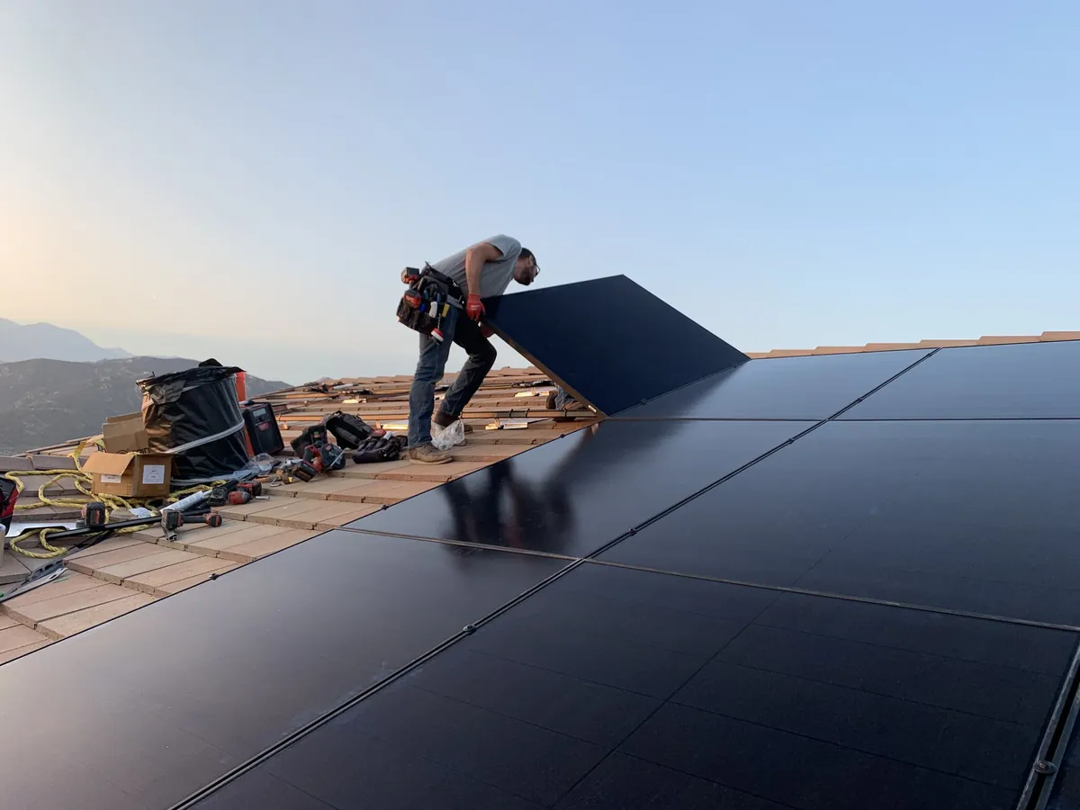 Solar panel installation crew working on a residential roof at golden hour